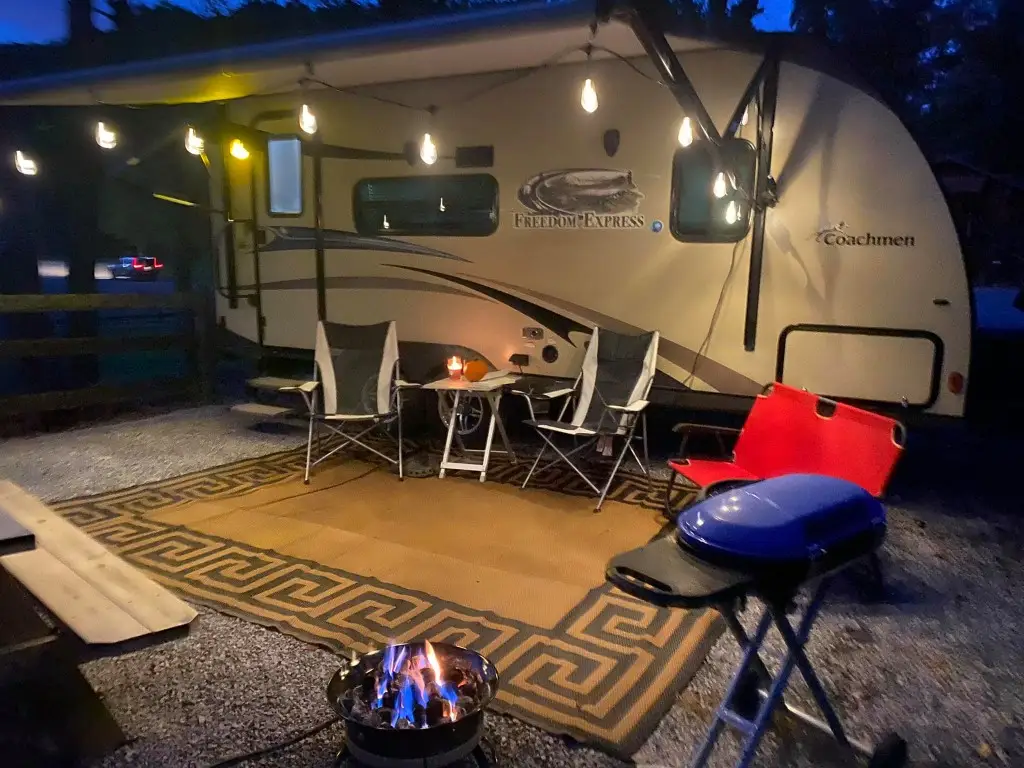 Silver travel trailer at a partial hookup site at dusk with campfire – Partial Hookup RV Site at The Outpost NRG