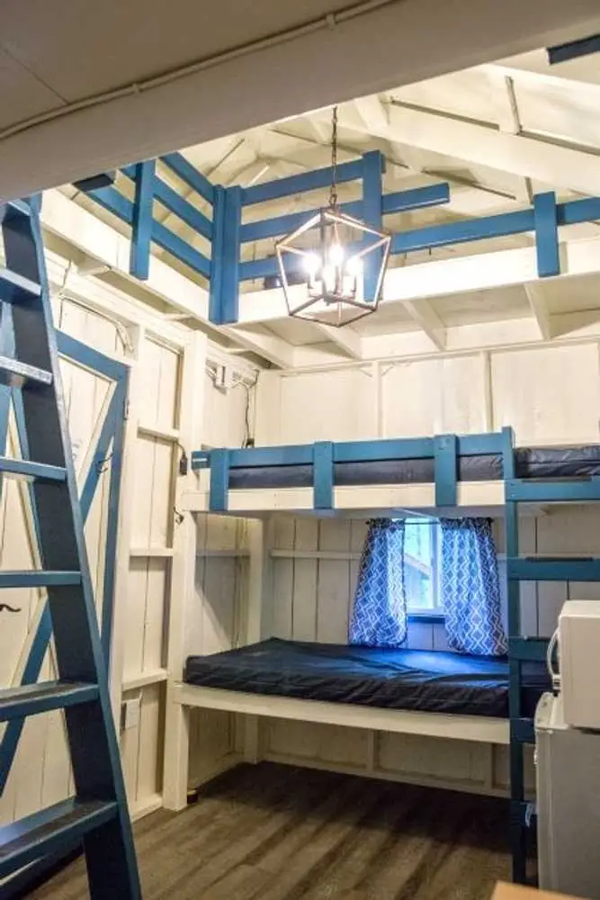 Blue bunk beds and loft ladder in the Big Family Cabin – Rustic Big Family Cabin at The Outpost NRG
