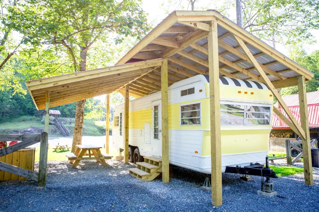 Mellow Yellow vintage camper under a covered wooden pavilion – Mellow Yellow Vintage Camper at The Outpost NRG