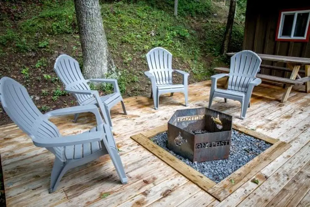 Deck with Outpost fire ring and Adirondack chairs – Rustic Bunk Cabin at The Outpost NRG