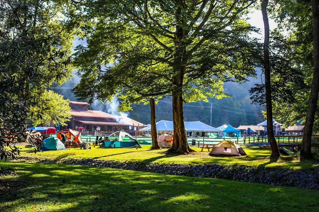 Tents in the field with the lodge in the background – Tent Sites at The Outpost NRG