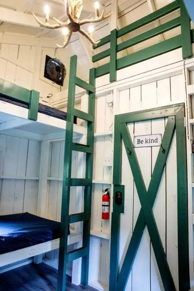 Green bunk beds and loft ladder inside the Bunk Cabin – Rustic Bunk Cabin at The Outpost NRG