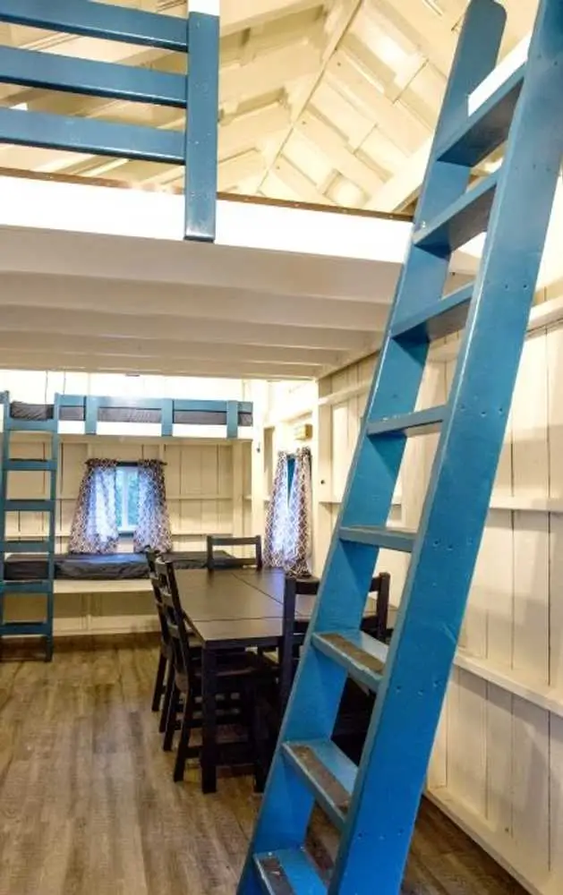 Living area with dining table and loft ladder – Rustic Big Family Cabin at The Outpost NRG