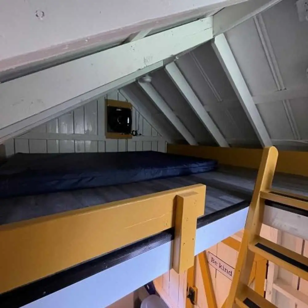 Queen loft mattress with yellow safety rail – Rustic Family Cabin at The Outpost NRG