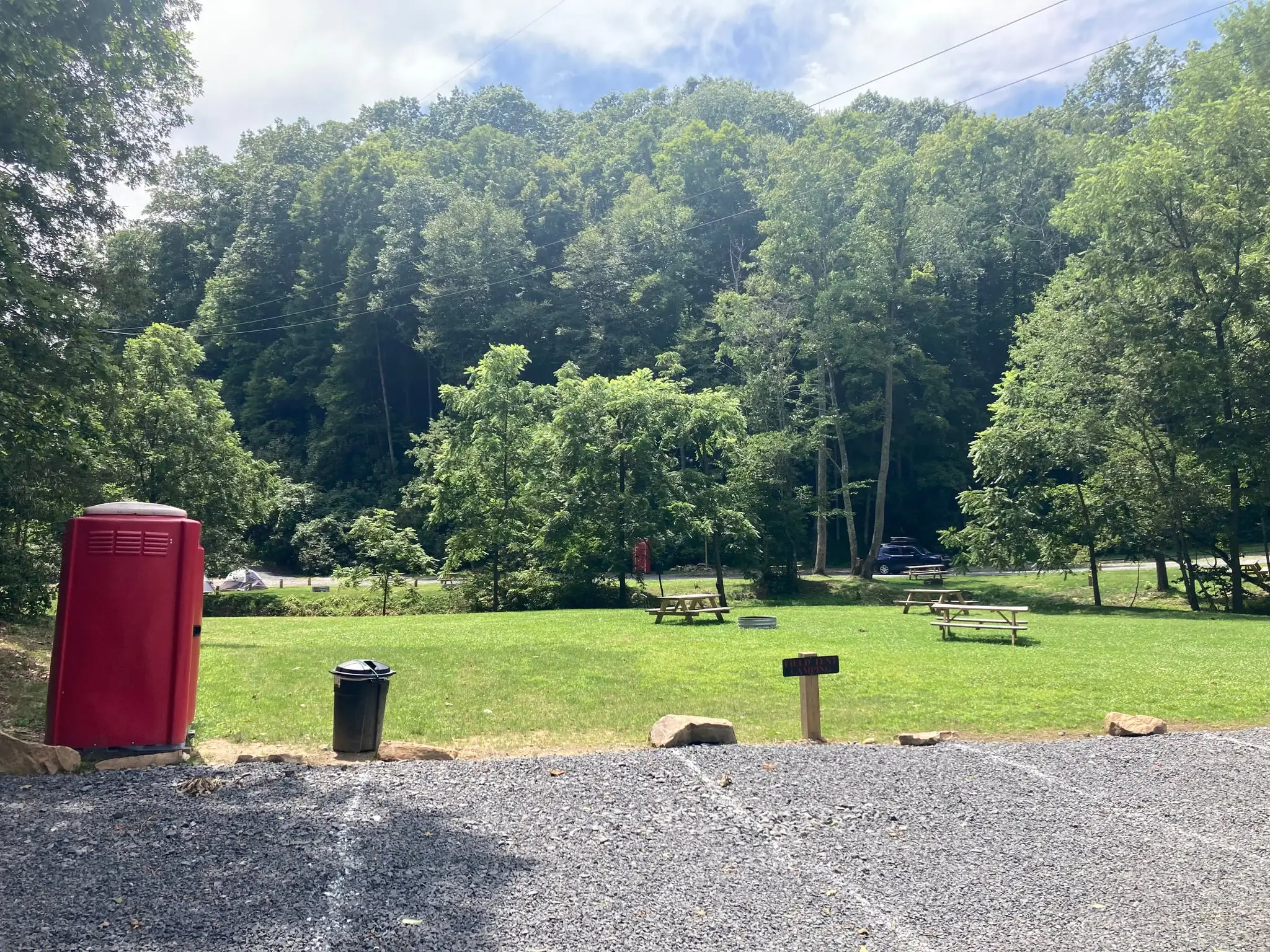 Open meadow with picnic tables and fire ring – Field Tent Camping at The Outpost NRG