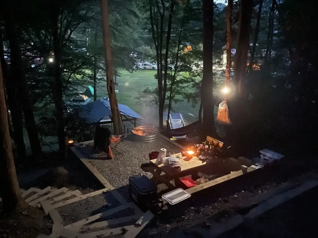 Tent platform at night with fire pit, picnic table, and hammock – Tent Platforms at The Outpost NRG