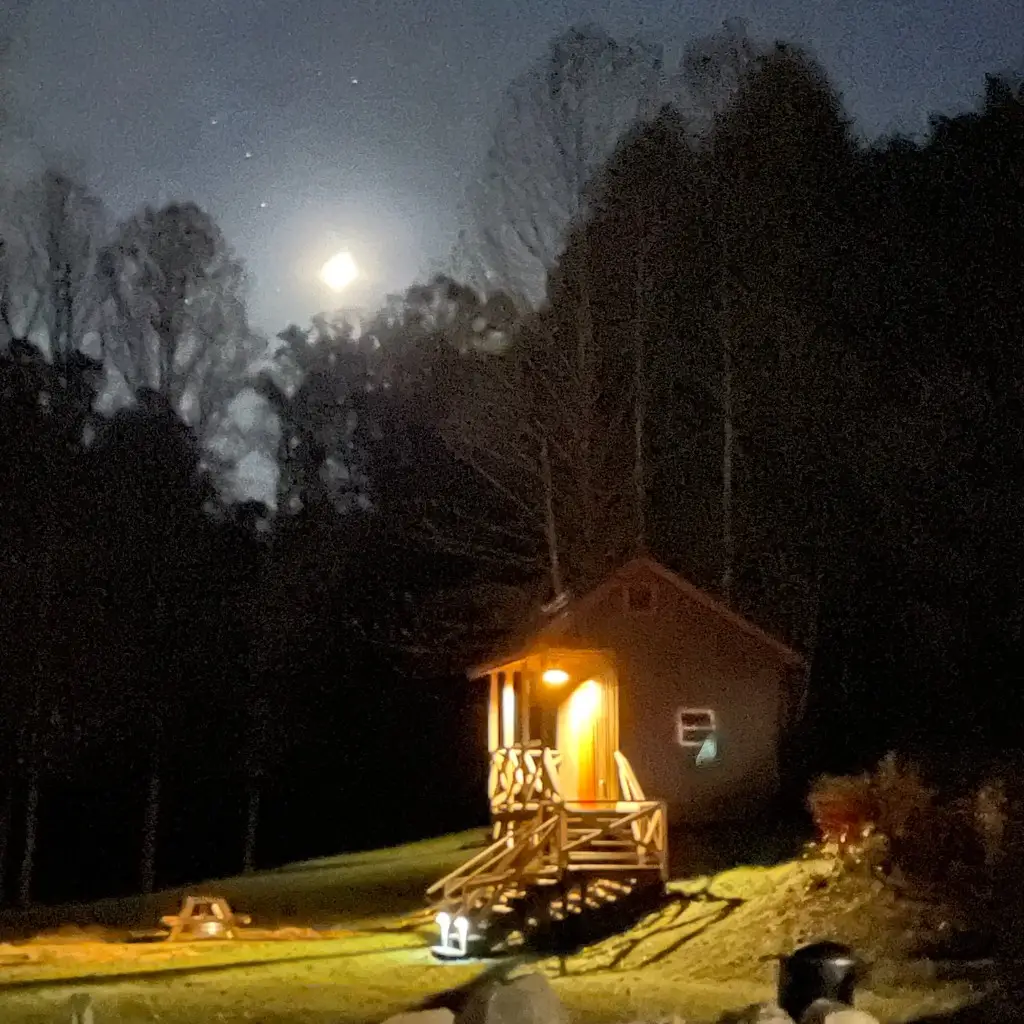 Rustic Family Cabin at night with porch light and moon – Rustic Family Cabin at The Outpost NRG