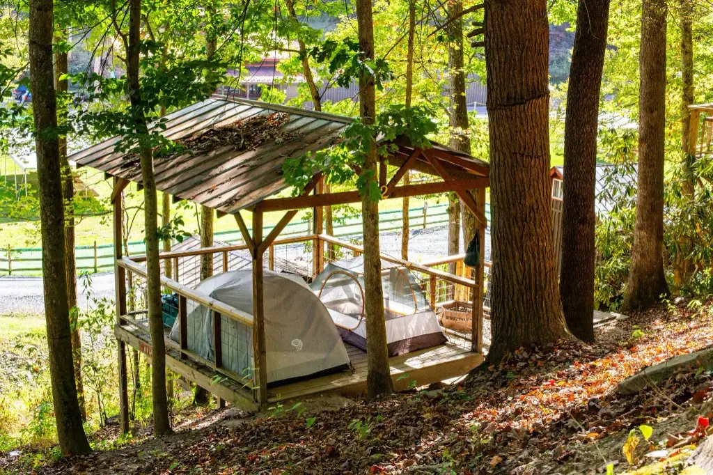 Covered wooden tent platform with two tents in the woods – Tent Platforms at The Outpost NRG