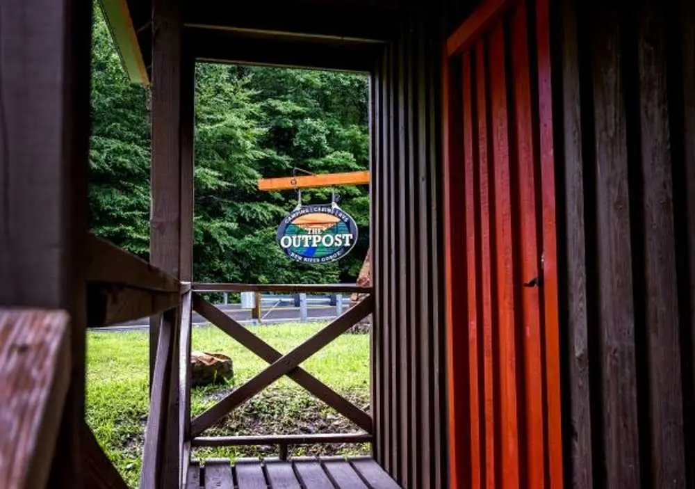 Porch view of The Outpost sign from the attached cabin – Partial Hookup RV with Rustic Family Cabin at The Outpost NRG