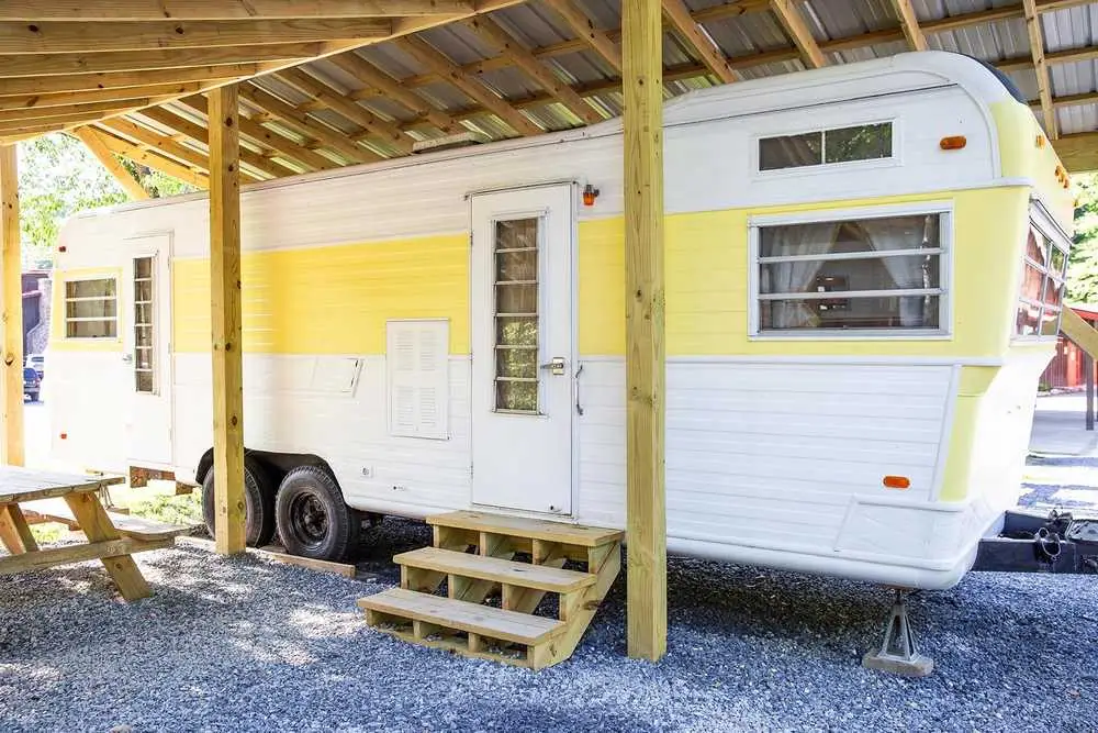 Mellow Yellow vintage camper under a wooden shelter – Mellow Yellow Vintage Camper at The Outpost NRG