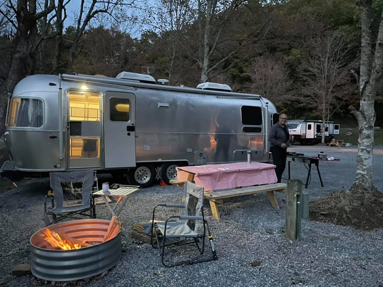 Partial hookup RV campground with gravel sites and wooded hillside – Partial Hookup RV Site at The Outpost NRG