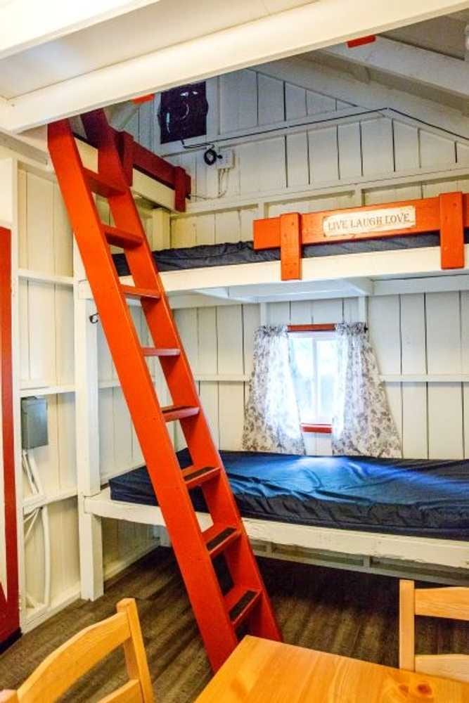 Orange bunk beds and ladder in the attached rustic family cabin – Partial Hookup RV with Rustic Family Cabin at The Outpost NRG