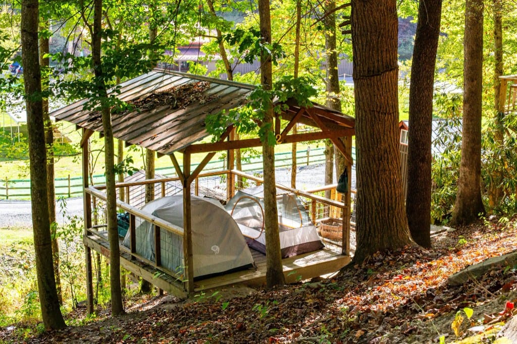 Covered wooden tent platform with two tents in the woods – Tent Platforms at The Outpost NRG