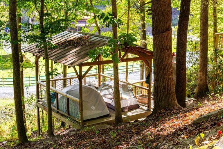 Covered wooden tent platform with two tents in the woods – Tent Platforms at The Outpost NRG