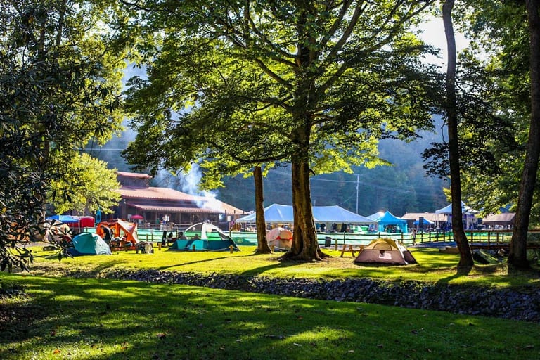 Tents in the field with the lodge in the background – Tent Sites at The Outpost NRG