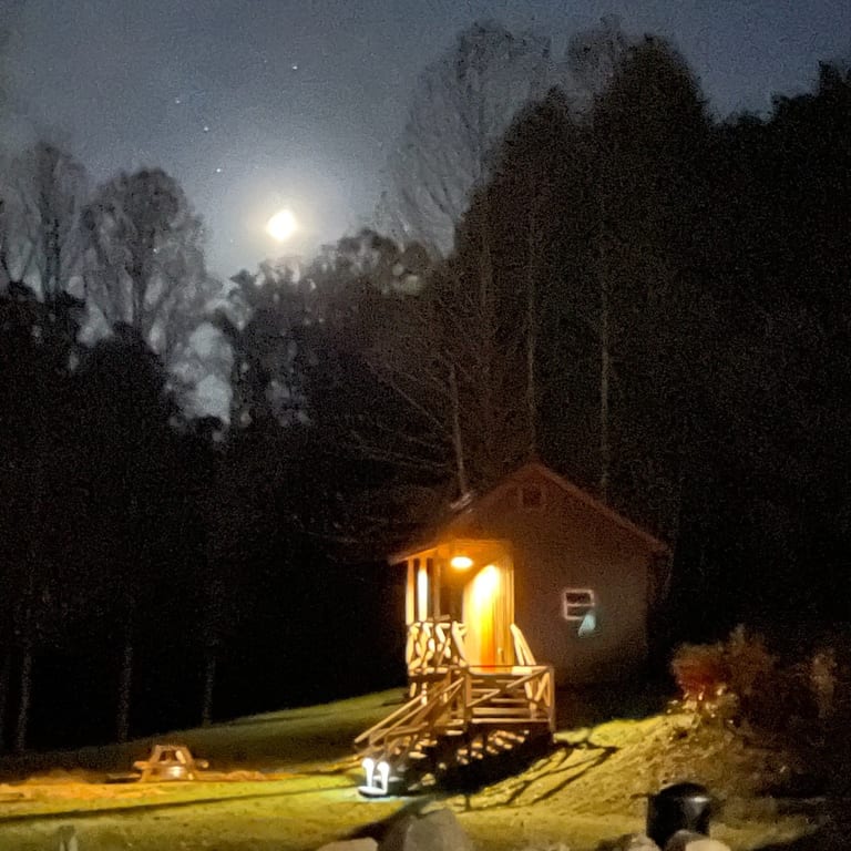 Rustic Family Cabin at night with porch light and moon – Rustic Family Cabin at The Outpost NRG